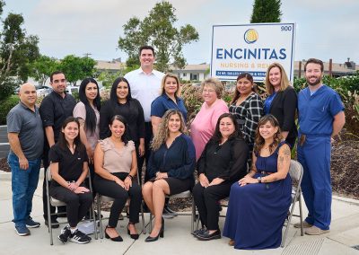 Team, staff, and executives at the front of the Encinitas Nursing and Rehab facility showing the sign